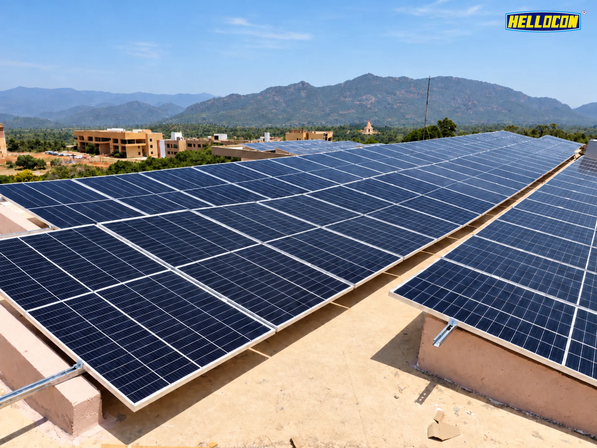 HELLOCON 100 kWp rooftop solar plant in Ganjam: low-tilt panel tables on a flat roof with hills behind